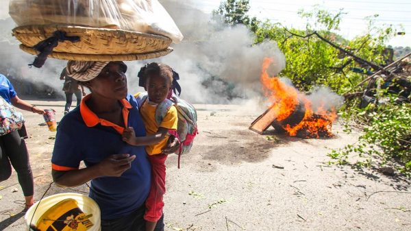 Una mujer con una niña pasan junto a una barricada en llamas, en Puerto Príncipe. - Patrice Noel/ZUMA Press Wire/dpa